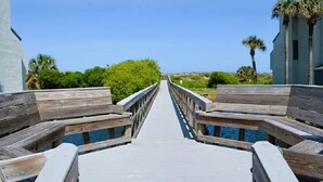Un muelle de madera que conduce a una masa de agua, bordeado por edificios y vegetación.