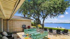 A patio with outdoor furniture, a grill, and a view of the water. - Amazing Bay by Ryson Vacation Rentals (Galveston)