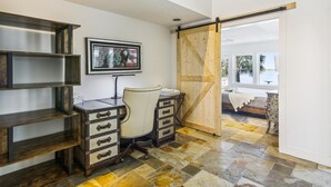 A room with a desk, chair, and a large wooden door leading to a balcony. - Amazing Bay by Ryson Vacation Rentals (Galveston)