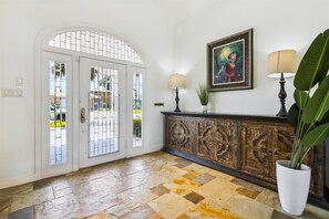 Enter a beautifully appointed space with an arched doorway leading to an outdoor area, a wooden cabinet, and a framed artwork.