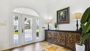A lobby with a stone floor, a wooden cabinet, a framed painting, and a potted plant. - Amazing Bay by Ryson Vacation Rentals (Galveston)
