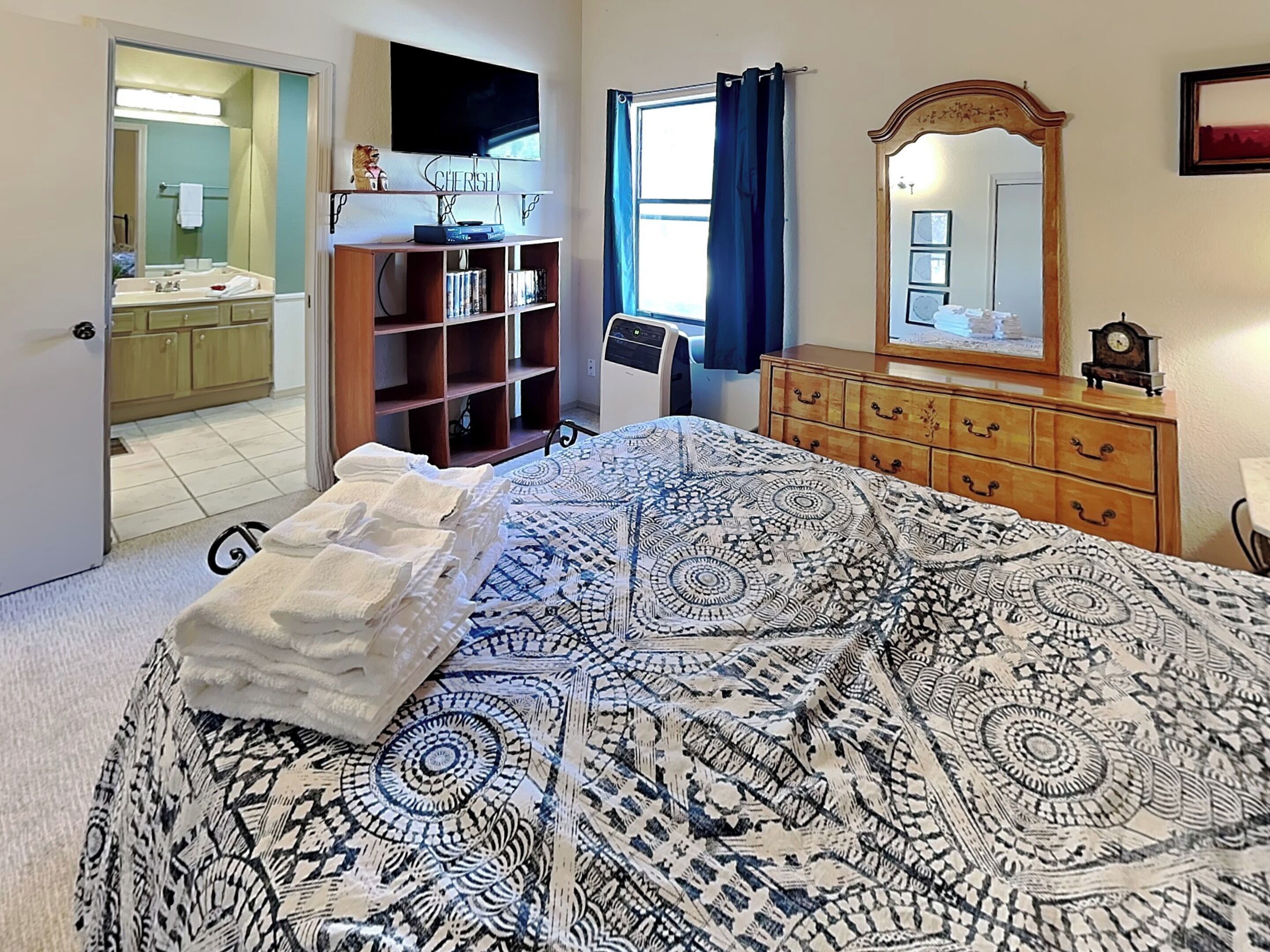 Un dormitorio con cama, cómoda y televisor montado en la pared.