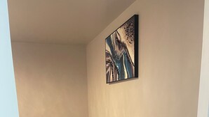 A dark leather sofa with patterned cushions, a large potted plant, and a piece of abstract art on the wall. - Cozy 1-bedroom Apt with WiFi and beautiful backyard view (Belleville)