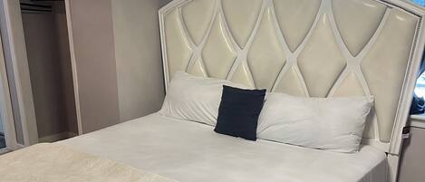 Una cama bien hecha con una colcha estampada y un cabecero con diseño de diamantes.