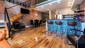 Ein modernes Loft mit freiliegenden Backsteinwänden, einer Holztreppe, einer Bar mit Hockern und einem Essbereich mit Stühlen.