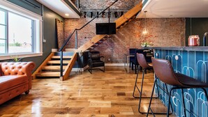 Ein modernes Interieur mit Backsteinwand, Holztreppe, Ledersofa und Barbereich.