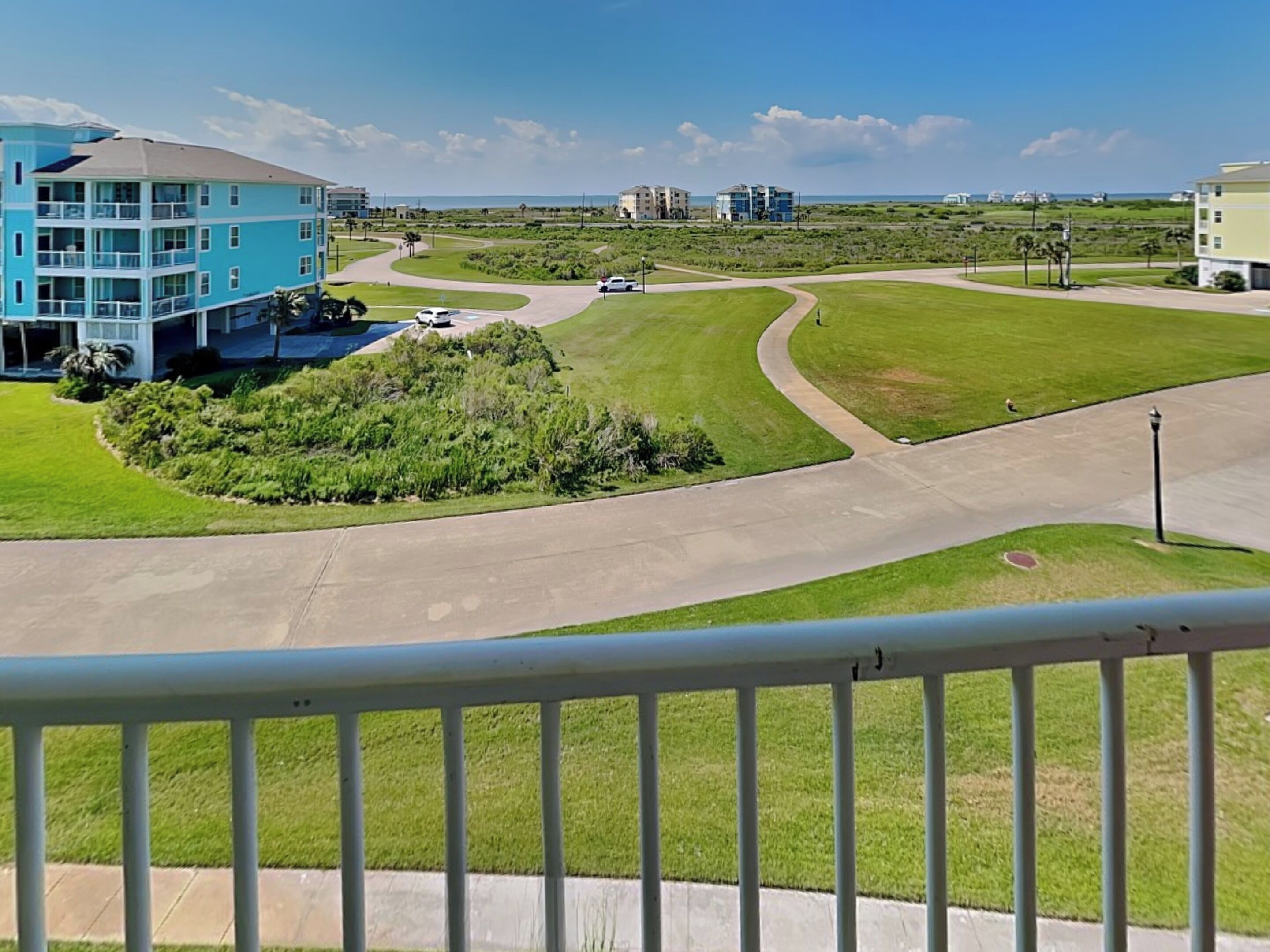 Un barrio residencial con un edificio azul, una carretera curva y vista al océano.