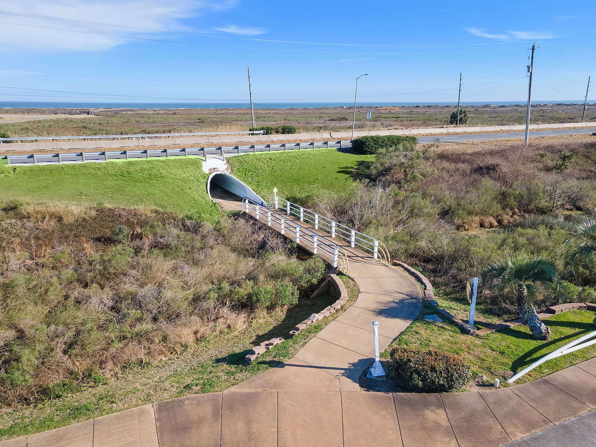 Een voetgangersbrug over een weg, met uitzicht op de oceaan op de achtergrond.