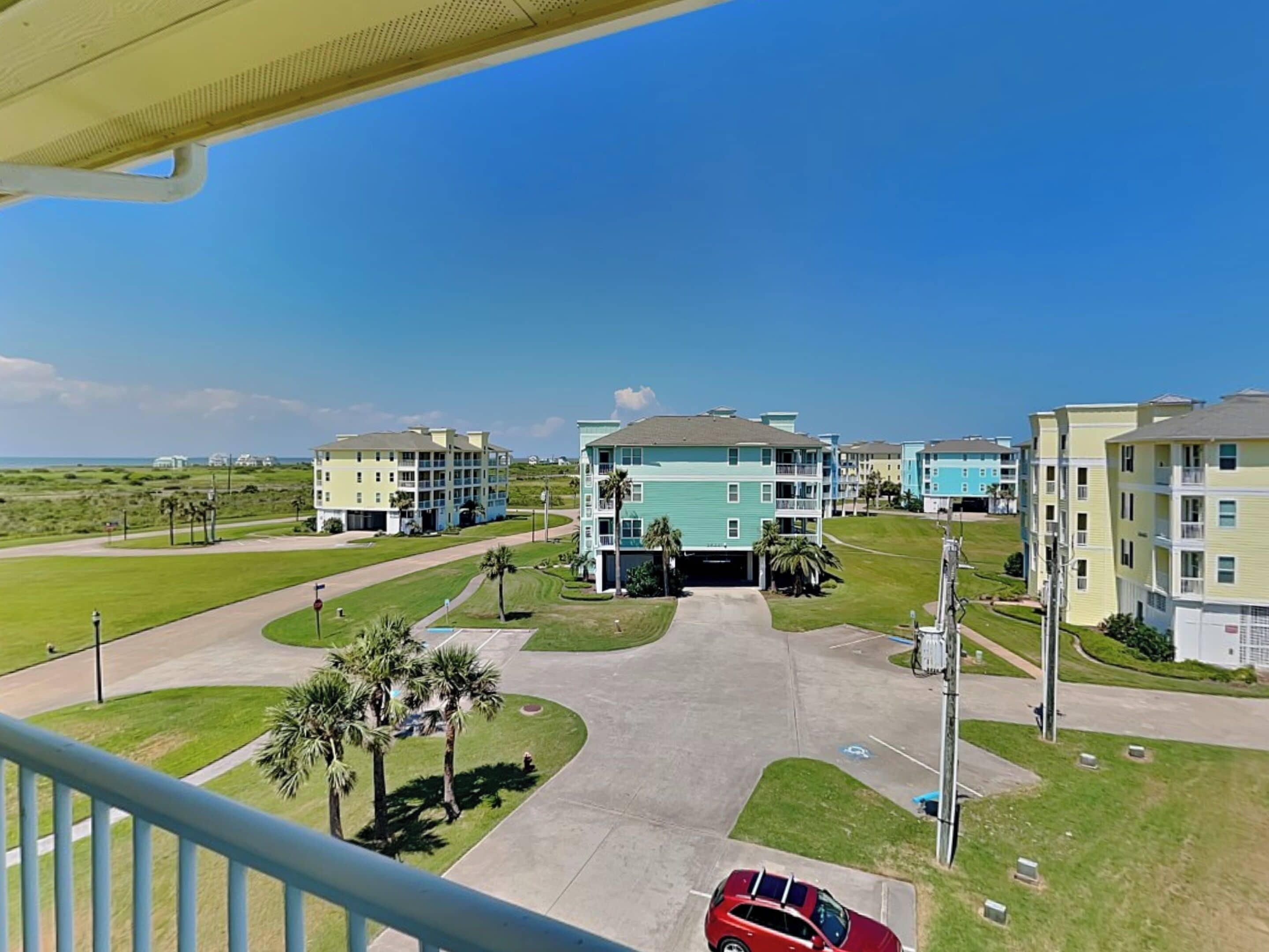 A view of a residential area with multiple apartment buildings, a parking lot, and a clear sky.