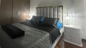 Ein modernes Schlafzimmer mit einem großen Bett, einem Nachttisch und einem Kleiderschrank.