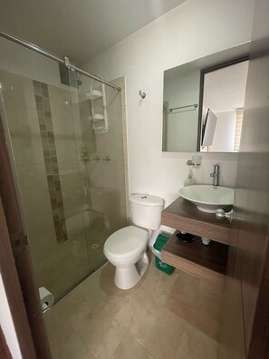 Une salle de bain avec une douche à parois de verre, des toilettes et un lavabo avec un miroir au-dessus.