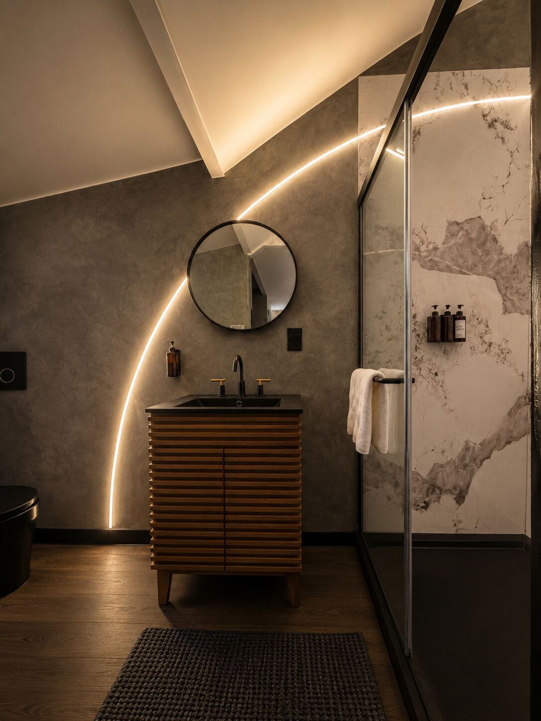A modern bathroom with a wooden vanity, a round mirror, and a glass shower enclosure.