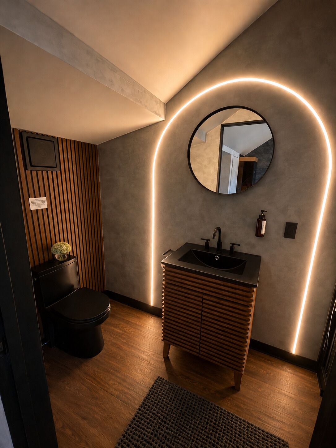 A modern bathroom with a wooden vanity, a round mirror, and a toilet.
