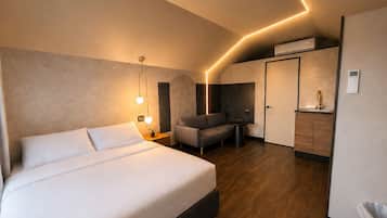 Ein modernes Hotelzimmer mit einem großen Bett, einer Sitzecke, einer Küchenzeile und einem Badezimmer.