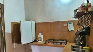 Une cuisine compacte équipée d’un réfrigérateur, d’une machine à café, d’une cuisinière à gaz et d’un évier.