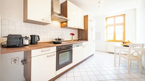 Et moderne køkken med hvide skabe, en indbygget ovn og en kaffemaskine.