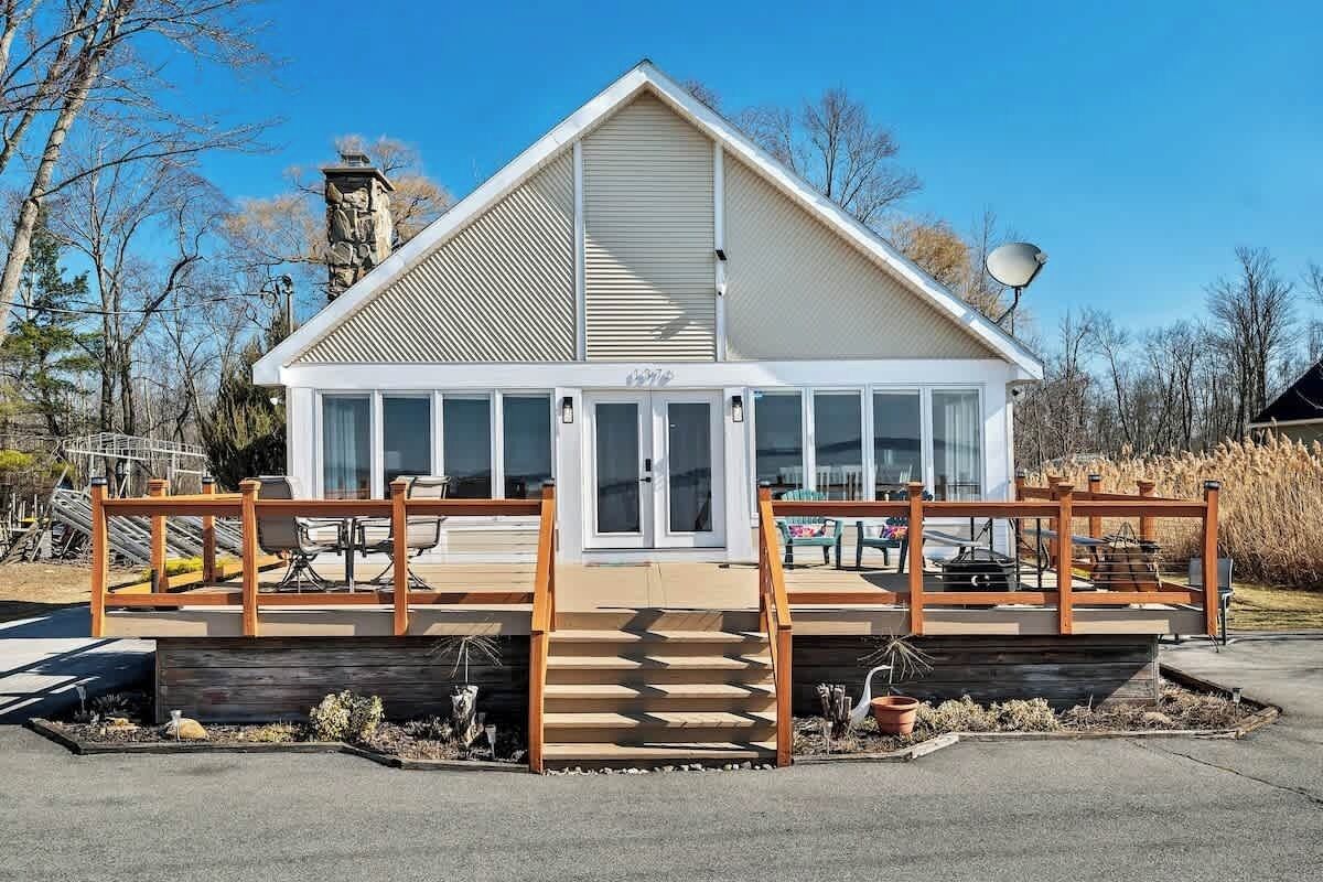 Un bâtiment moderne doté d’un toit en pente, de grandes fenêtres et d’une terrasse en bois avec des marches menant à l’entrée.