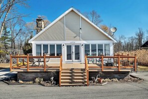 A modern building with a sloped roof, large windows, and a wooden deck with steps leading to the entrance. - Lakeside Retreat on Saratoga Lake (Saratoga Springs)