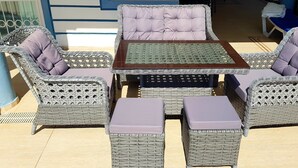 Un espace extérieur aménagé avec des meubles en osier, comprenant des chaises rembourrées et une table.