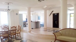 Un vaste espace de vie doté d’un sol à carreaux, d’un canapé, d’une table basse en verre et de chaises en bois.