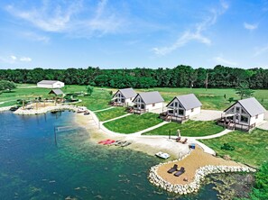 Un complexe hôtelier au bord du lac, comprenant plusieurs chalets, une zone de baignade et un quai.