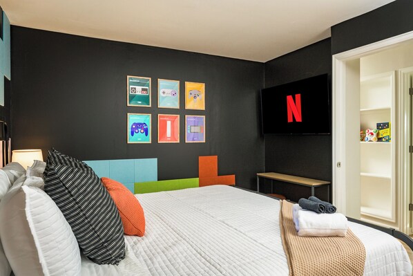 A modern hotel room with a large bed, a flat-screen TV mounted on the wall, and a door leading to a bathroom.