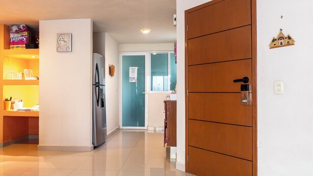 A hallway with a refrigerator, a wooden door, and a wall clock. - New Cancun Oasis Sunsets Near the Beach (Cancun)
