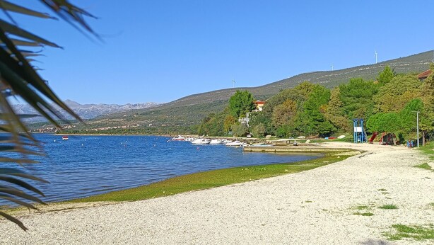 A beach with a pebble shore, boats in the water, and a playground.