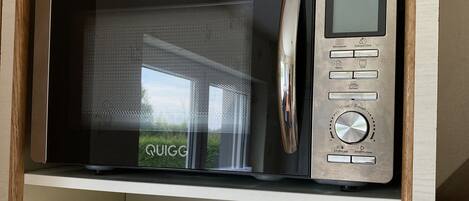Un four à micro-ondes doté d’un écran numérique, d’un panneau de commande et d’un compartiment situé en dessous.