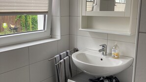 Une salle de bain moderne avec un lavabo blanc, un miroir et un porte-serviettes.