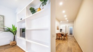 Un intérieur moderne avec des étagères blanches, un coin repas avec des chaises en bois et une cuisine en arrière-plan.