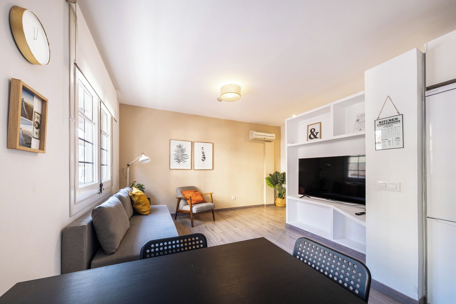 A modern apartment with a dining area, a sofa, a TV, and a kitchen.