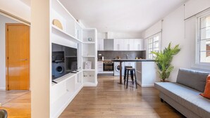 Une cuisine moderne avec des meubles blancs, un îlot central et un lave-linge encastré.