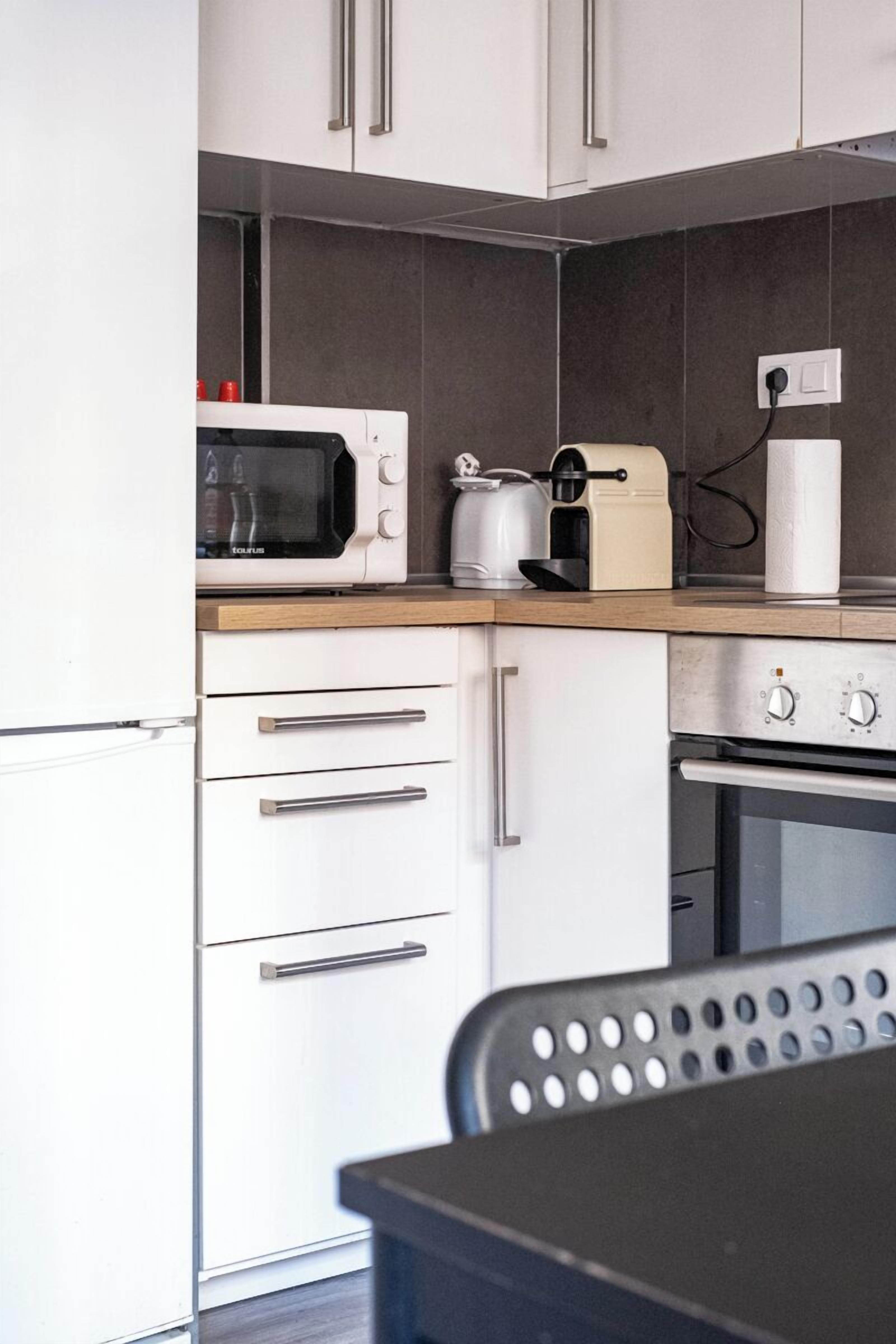 A modern kitchen with white cabinets, a microwave, a toaster, and an oven.
