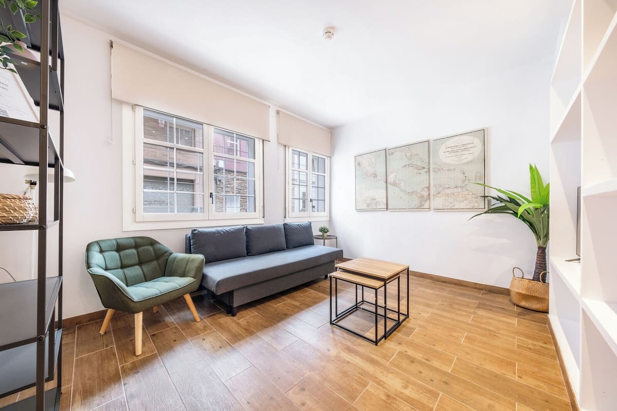 Un salon moderne avec un canapé, un fauteuil, une petite table et une plante en pot.