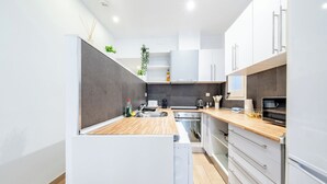 Une cuisine moderne avec des armoires blanches, un plan de travail en bois et des appareils électroménagers en acier inoxydable.