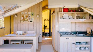 Een gezellig, goed verlicht verblijf in tentstijl, met een kitchenette, een eethoek en een kleine zithoek.