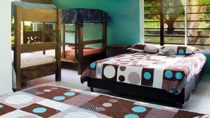 A bedroom with bunk beds, a bed with a patterned quilt, an air conditioner, and a window with a view of greenery. - Finca club las palmas en Girardot (Girardot)