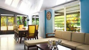 A spacious living area with a sofa, a dining table with chairs, and a large window with a view of greenery. - Finca club las palmas en Girardot (Girardot)