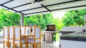 An outdoor patio with a dining table and chairs, a grill, and a water feature. - Finca club las palmas en Girardot (Girardot)