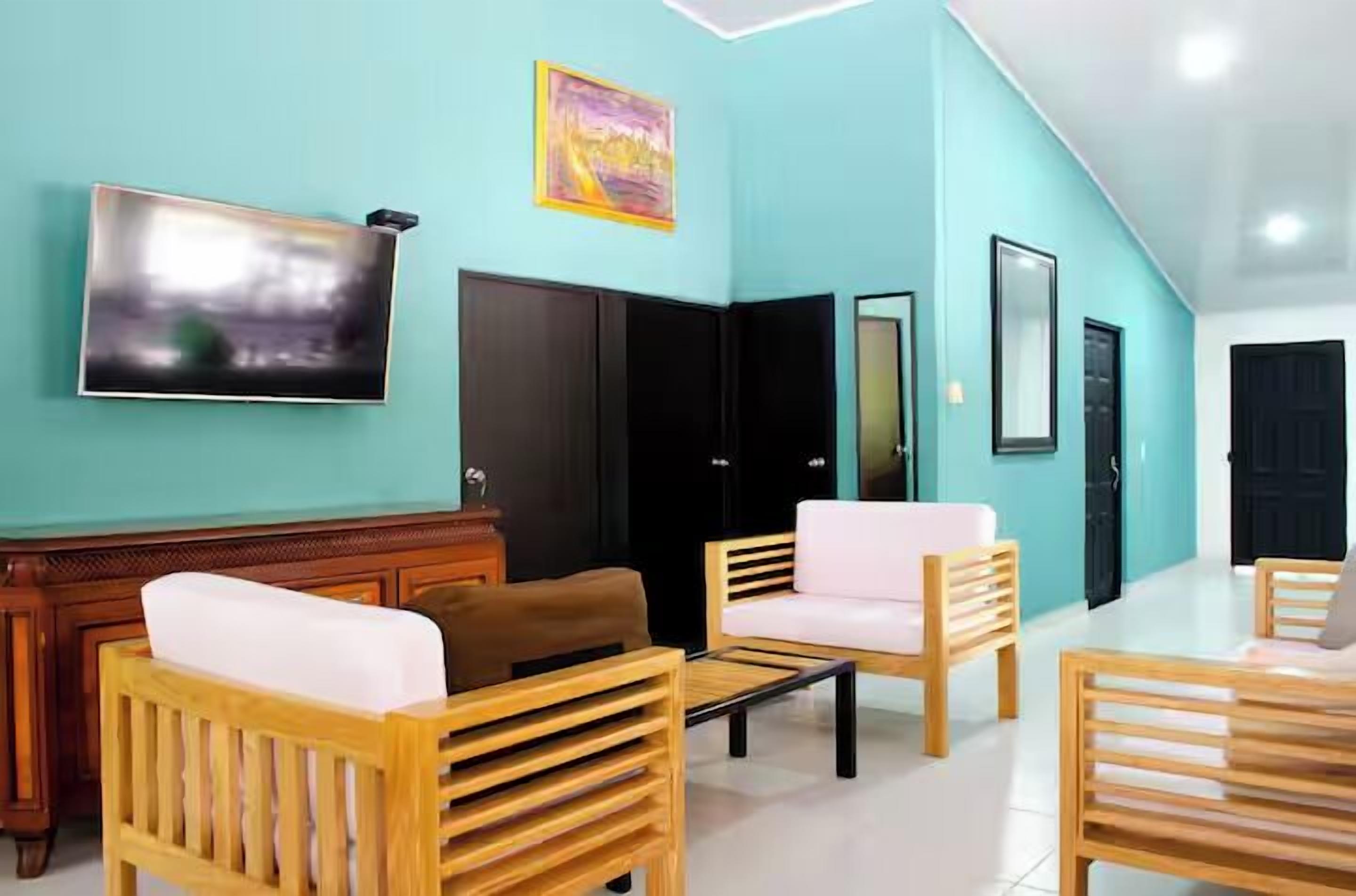 Un moderno vestíbulo de hotel con paredes verde azulado, muebles de madera y un televisor de pantalla plana grande.