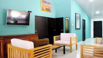 Un moderno vestíbulo de hotel con paredes verde azulado, muebles de madera y un televisor de pantalla plana grande.