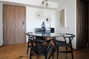 A dining area with a round glass table, black chairs, a wooden door, and wall decor.