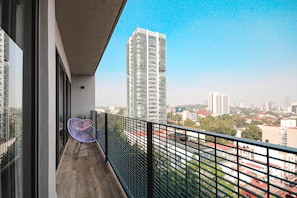 A balcony with a view of a cityscape, including a tall building with a unique architectural design.