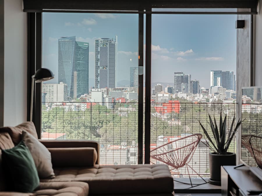 Una sala de estar moderna con un ventanal grande, un sofá, una silla y una planta en maceta.
