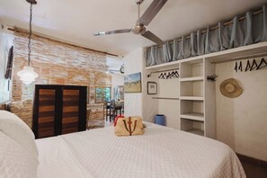 Ein Schlafzimmer mit Bett, Kleiderschrank, Deckenventilator und einer Wand mit einer Pendelleuchte.