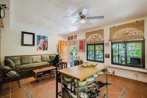 A living room with a sofa, a dining table, and a kitchen area with a window.
