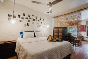 A bedroom with a bed, a wardrobe, a hanging light fixture, and a wall adorned with photographs.