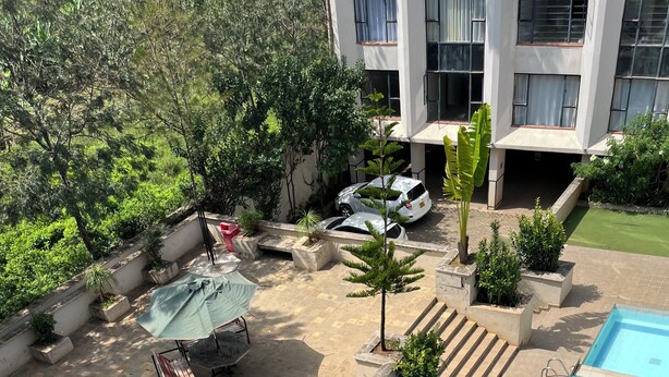 Ein Swimmingpool mit Sonnenschirm, einer überdachten Sitzgelegenheit und einer Treppe zu einem Gebäude.