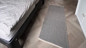 Et soveværelse med seng, stol, radiator og en dør til et andet rum.